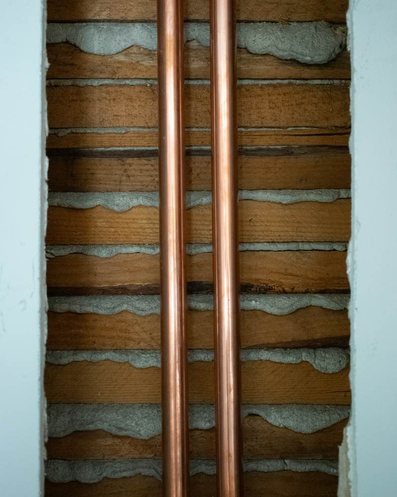 Two new copper supply lines running up an opened brick wall