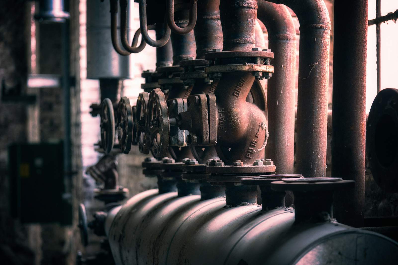 Row of heavy valves and pipe flanges in an old boiler room